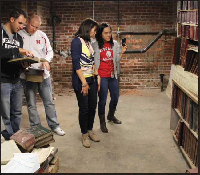 Above: Business teachers Nick Madsen, Collin Hute,
Special Education Teacher Linda Johnson-Flowerday, and
Social Studies teacher Donna Anderson look through old
books found in a basement storage area during a tour of
hidden places at LHS led by IB coordinator John Heineman.
Photo by Greg Keller