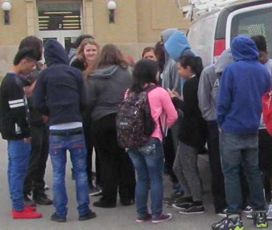 Students and staff huddle behind a CMF truck in the east parking lot to keep warm after a fire in the Pool Hallway set off alarms Thursday morning. Near-freezing temperatures made the almost 15 minutes outside very uncomfortable. 