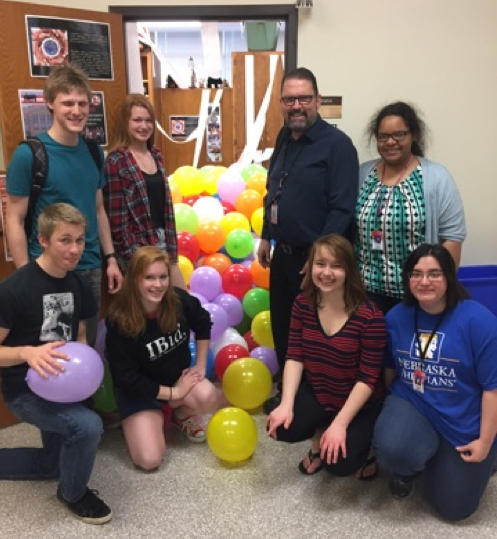 Retiring IB Coordinator John Heineman poses with the students who filled his office with balloons and toilet paper for April Fools Day. 