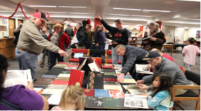 LHS alumni pour over the pile of yearbooks in the Media Center during the 100 Years on J Street Open House on March 29, 2015. The even attracted hundreds of guests. Photo by Greg Keller