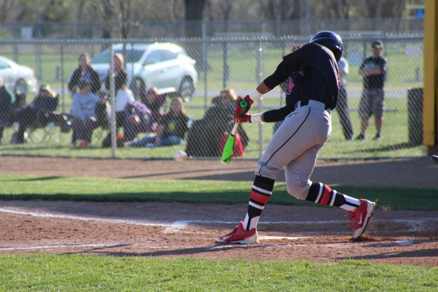 Aundra+Gilbert+%2812%29+hits+the+ball+in+a+varsity+game+against+Lincoln+Southwest+on+April+4th.+Photo+by+Michael+Ourada