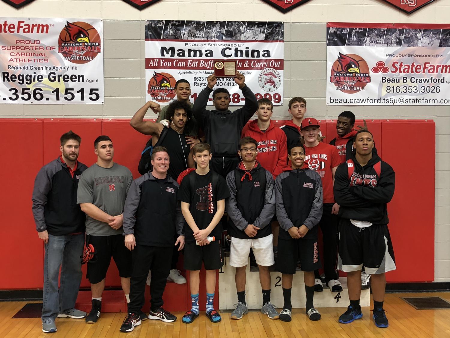 The Links Varsity Wrestling team lines up for a photo as they raise up their 3rd place trophy on December 17, 2017. Photo courtesy of Camden Trevarrow.