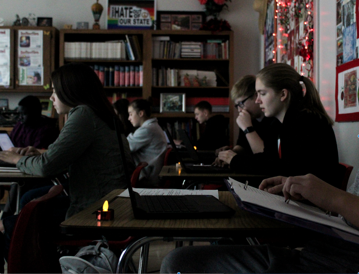 Lydia Skold (left), Jack Amen (right back ) and Olivia Haller (right front) write by candlelight in Deborah McGinn's 9th grade Pre-IB English class. Photo by Maicee Ingwerson