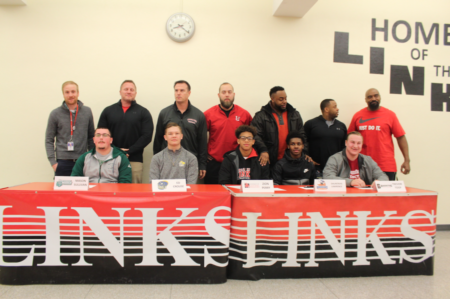 Student-Athletes from Lincoln High School sign to play football at the next level on February 7, 2018. Left to Right: Mason Sullivan, Ed Crouse, Zion Perry, Dontavious Lawrence, and Trevor Toof. The coaches behind the players include Coach Jared Shaw, Coach Chad Case, Coach Mark Macke, Coach Dan Beckmann, Coach John Goodwin, Coach James Watson and Coach Stewart Venable. Photo by Hannah Burianek.