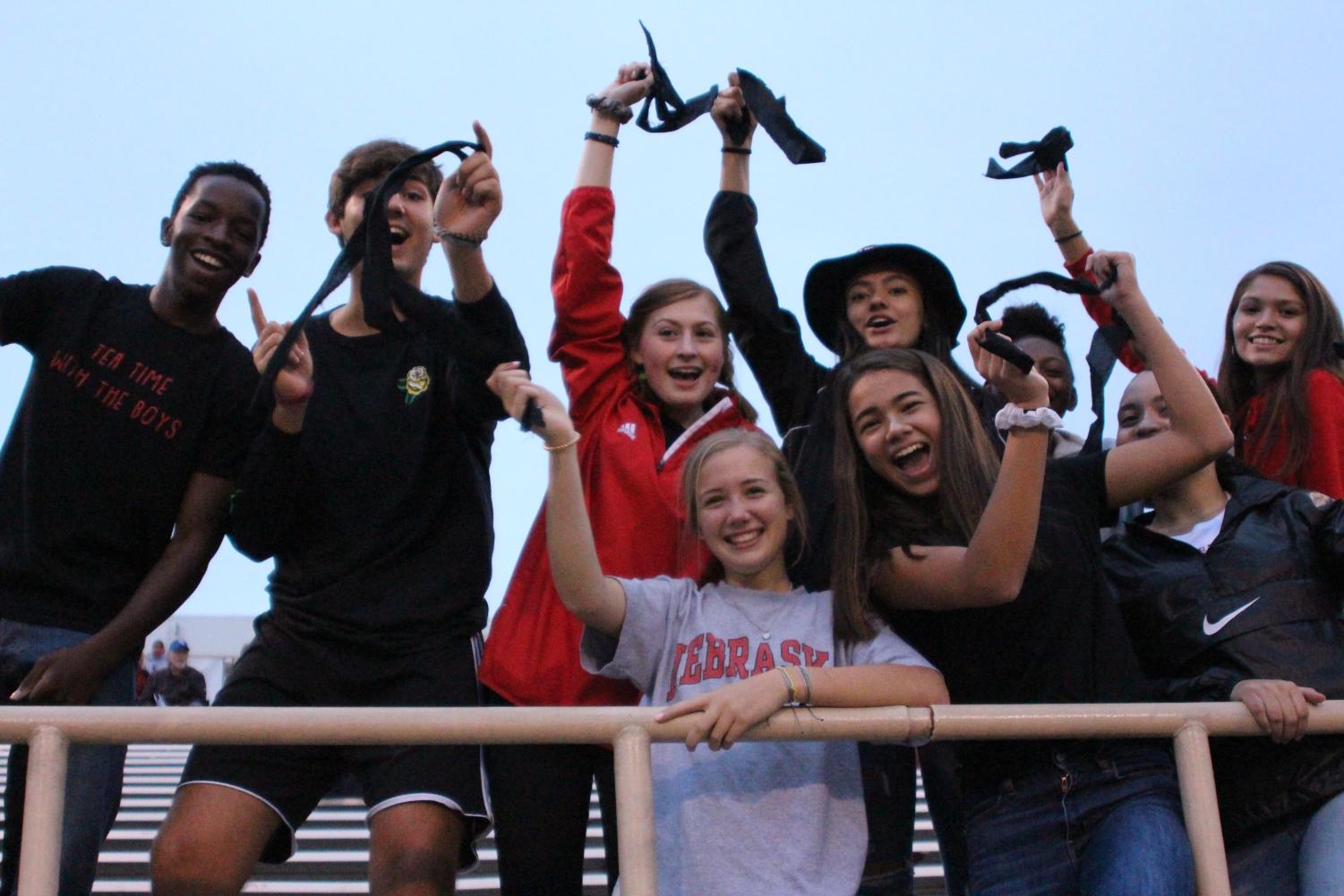 From left to right: Passmore Mudundulu (12), Jack Maynard (12), Joey Caruso (12), Katie Smith (10), Cecilia Chada (12), Lydia Skold (10), Naenae Wynn (11), Alena Isley (11), and Naomi Rodriguez (11) rep their black headbands made by Zeke Williams and Tyler Schumacher at the varsity football game against Creighton Prep at Omaha Burke on Friday, September 7th, 2018. Photo by Zeke Williams.