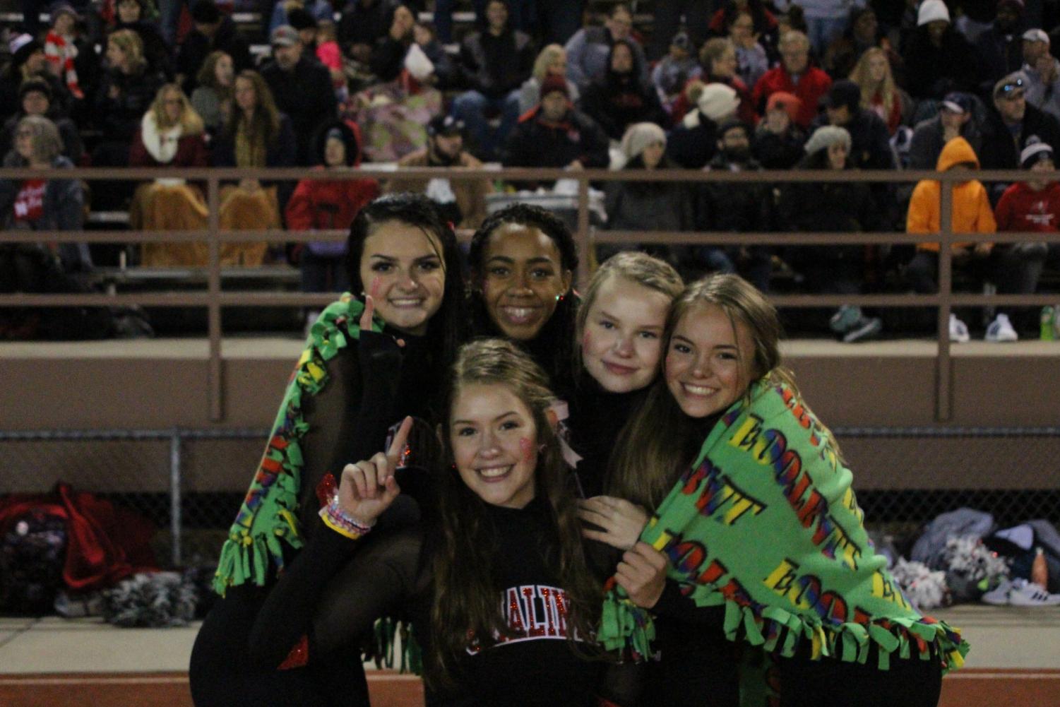 (From Left to Right) Pomalinks Maddie Behrens (11), Zainab Funnah (9), Bridget Wilson (10), Bailey Hanson (10) and Regan Schneider (11) try to stay warm before performing their halftime show for the varsity football game at Lincoln High on October 12th against the Kearney Bearcats. The Links won 66-31. Lows Friday night reached 38 degrees Fahrenheit. Photo by Zeke Williams