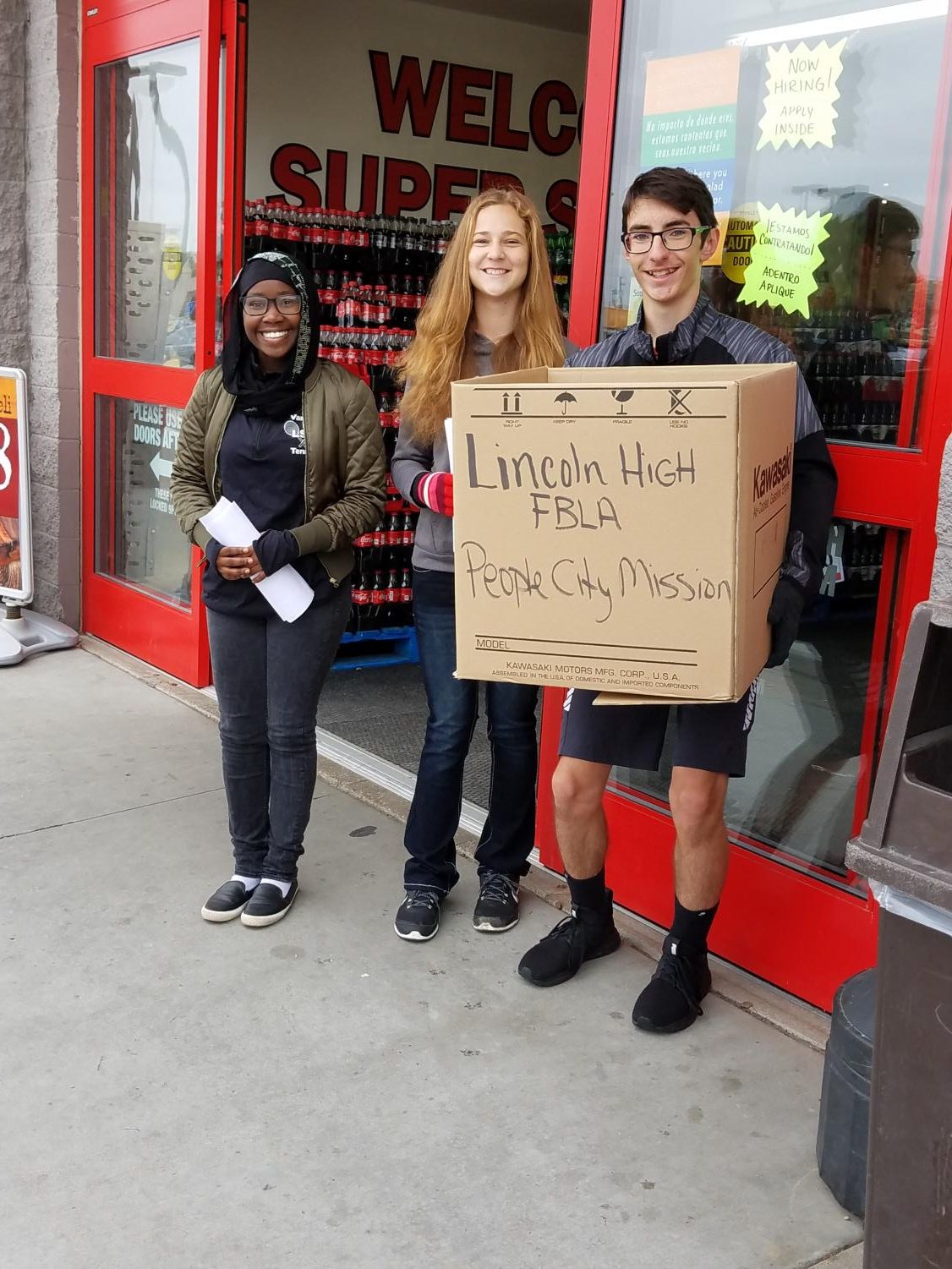 (Left to Right) Meissa Hassan (10), Aspen Kenley (9), and Ethan Fleming (9) pose with the boxes of food they collected at the 27th and Cornhusker Super Saver for the FBLA Food Blitz fundraiser for the Lincoln People’s City Mission on Oct. 6, 2018. Photo courtesy of Bonnie Anderson