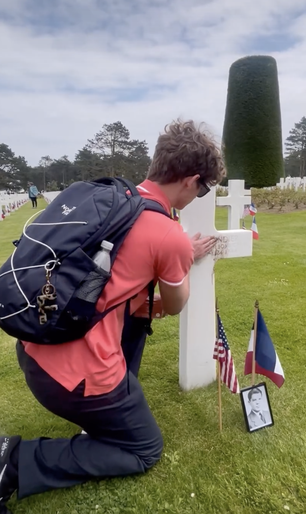 Cole Butler (12) rubs dirt brought from Lincoln High School into the burial marker at the Normandy American Cemetery at the 80th anniversary of D-Day on Thursday.