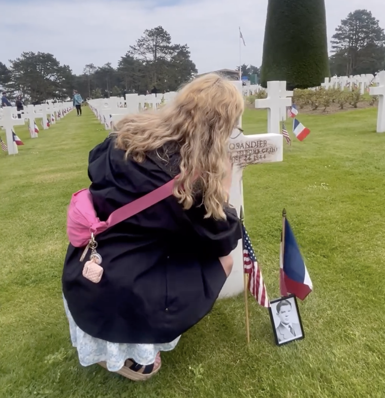 Faye Harpham (LNE '24) rubs dirt brought from Lincoln High School into the burial marker at the Normandy American Cemetery at the 80th anniversary of D-Day on Thursday.