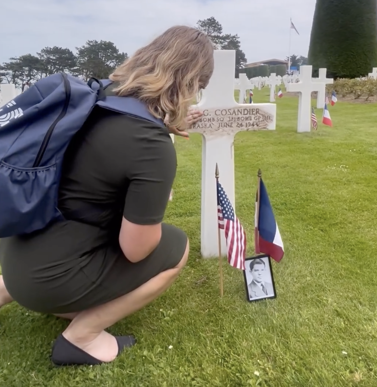 Rowan Wick (12) rubs dirt brought from Lincoln High School into the burial marker at the Normandy American Cemetery at the 80th anniversary of D-Day on Thursday.