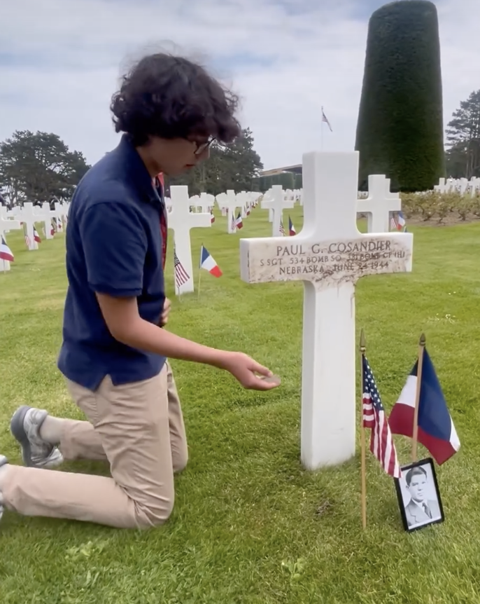 Jared Obidowski (12) rubs dirt brought from Lincoln High School into the burial marker at the Normandy American Cemetery at the 80th anniversary of D-Day on Thursday.